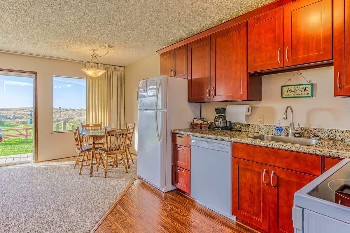 A kitchen with wooden cabinets, a refrigerator, a coffee maker, and a sink.
