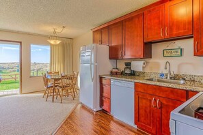 A kitchen with wooden cabinets, a refrigerator, a coffee maker, and a sink.
