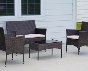 Une terrasse dotée de meubles en osier, notamment deux chaises et une petite table.