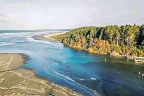 A river flowing through a forested area with a sandy beach on one side. - Hi-Tide Resort, Private Deck, Dogs OK, Unit 10 (Moclips)