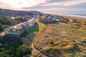 An aerial view of a coastal residential area with houses, a road, and a beach.