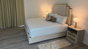 A bedroom with a bed, bedside tables, a rug, and curtains.