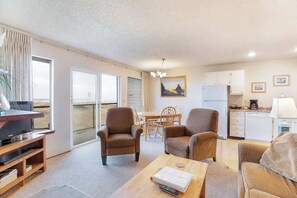A living room with a TV, two armchairs, a coffee table, and a dining area with a table and chairs.