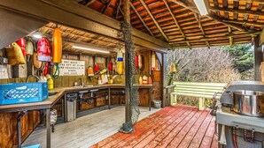 Une cuisine rustique avec des poutres en bois, des fruits de mer suspendus et une terrasse en bois.