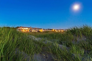 A beachfront property with multiple buildings, a clear sky, and a visible moon.