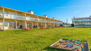 A hotel with a large grassy lawn, outdoor seating, and a playground area.