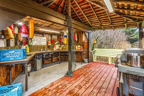 A rustic kitchen with wooden beams, hanging seafood, and a wooden deck.