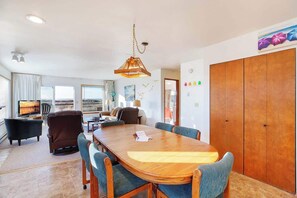 A spacious living area with a large wooden dining table, comfortable seating, a television, and a view of the outdoors. - Hi-Tide Resort, Queen Bed, Unit 12 (Moclips)