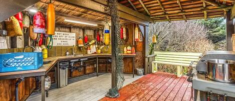 A rustic kitchen with wooden beams, hanging seafood, and a wooden deck.