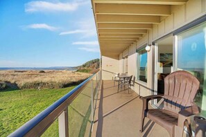A balcony with a view of the beach, a table, and a chair. - Hi-Tide Resort, Queen Bed, Unit 12 (Moclips)