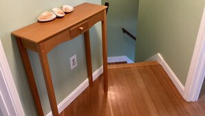 A wooden console table with a drawer, a light switch, and a small shelf with decorative items. - Ocean Front cape cod style home with panoramic views of North Beach. (Hampton)