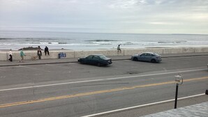 A coastal road with parked cars, a pedestrian walkway, and a view of the ocean. - Ocean Front cape cod style home with panoramic views of North Beach. (Hampton)