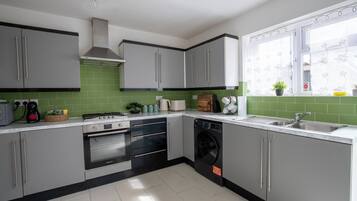 Eine moderne Küche mit grauen Schränken, einem eingebauten Ofen, einem Geschirrspüler und einem Fenster mit Blick.