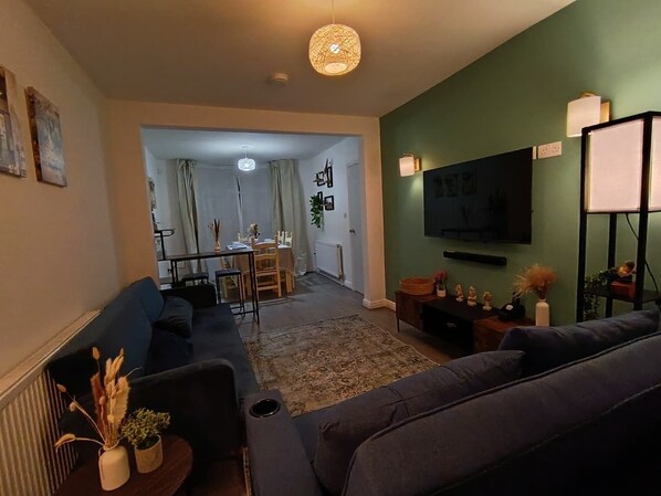 A living room with a sofa, a television, and a dining area with a table and chairs.