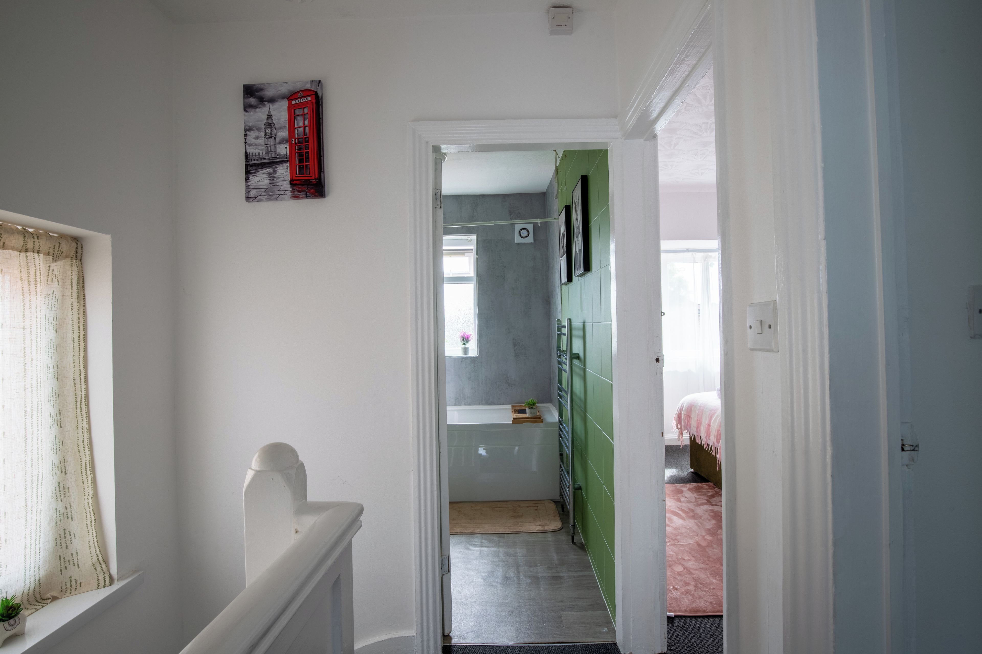 Ein Flur mit einer Tür zu einem Zimmer, das ein Bett und eine grüne Wand hat.