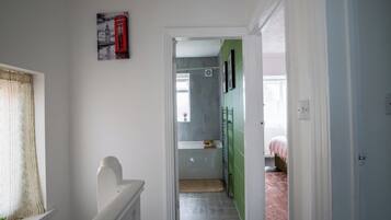 Ein Flur mit einer Tür zu einem Zimmer, das ein Bett und eine grüne Wand hat.