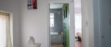 Un pasillo con una puerta que da a una habitación con una cama y una pared verde.