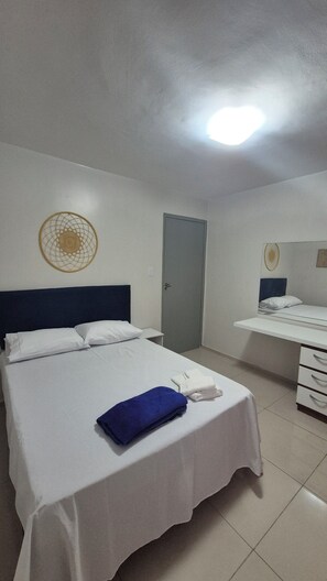 A hotel room with a bed, a desk, a chair, a door, and a wall decoration. - Comfortable apartment in Maceió (Maceió)