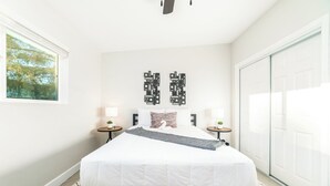 Een slaapkamer met een bed, twee nachtkastjes, een kunstwerk aan de muur en uitzicht op het omliggende landschap.
