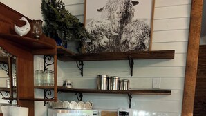 A kitchen with wooden cabinets, a microwave, a coffee maker, and a framed picture of sheep. - Cozy 1-bedroom cottage in lovely Rocky Mount with AC (Rocky Mount)