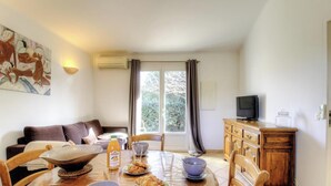 A dining area with a table set for two, a television on a wooden cabinet, and a painting on the wall. - Fiori d'Alivi - PORTO VECCHIO (PORTO VECCHIO)