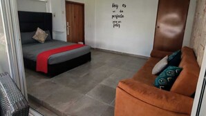 Ett rum med en säng, en soffa, en vägg med ett inspirerande citat och en dörr.