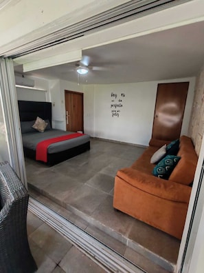 Una habitación con una cama, un sofá, una pared con una cita motivacional y una puerta.