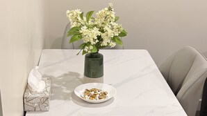 A dining table with a vase of flowers, a tissue box, and a plate of snacks. - The Dolak Comfort Homes - beautiful, cozy,new, close the airport, grocery stores (Calgary)