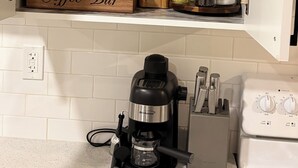 A kitchen with a coffee bar, a coffee maker, and various kitchen utensils. - The Dolak Comfort Homes - beautiful, cozy,new, close the airport, grocery stores (Calgary)