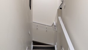 A staircase with wooden steps and white handrails, leading to a landing with a light fixture. - The Dolak Comfort Homes - beautiful, cozy,new, close the airport, grocery stores (Calgary)