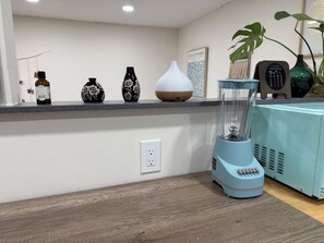Una encimera de cocina con una licuadora, una botella y jarrones decorativos.