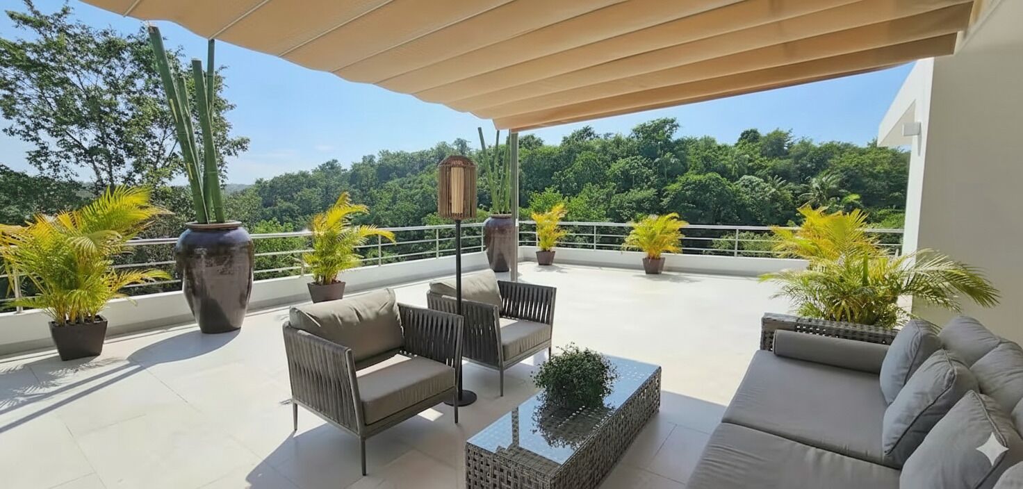 Une terrasse sur le toit, aménagée avec du mobilier d’extérieur, des plantes en pot et offrant une vue sur la verdure environnante.