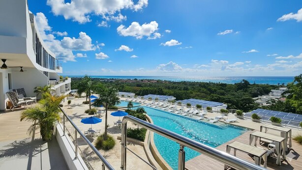 A modern hotel with a pool, sun loungers, and a view of the ocean. - MŪTE Collection at Spirit of Terrenas (Las Terrenas)