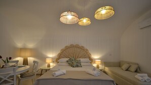 A hotel room with a bed, a sofa, a round table with chairs, and three pendant lights. - Petra Lavea (Pompei)