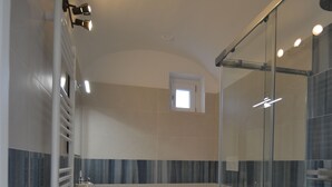 A modern bathroom with a glass shower enclosure, a white sink, and a toilet. - Petra Lavea (Pompei)
