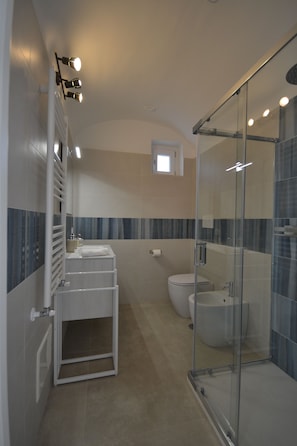 Ein modernes Badezimmer mit einer Duschkabine aus Glas, einem weißen Waschbecken und einer Toilette.