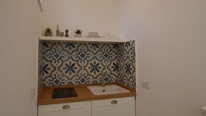 A small kitchen with a white countertop, a sink, and a decorative backsplash. - Petra Lavea (Pompei)