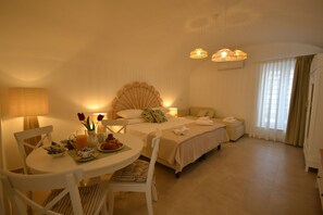A hotel room with a dining table, chairs, a bed with a canopy, a bedside table with a lamp, and a window with curtains. - Petra Lavea (Pompei)