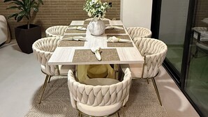 Un coin repas avec un mur en briques, une grande horloge murale, un vase de fleurs et une porte en verre.