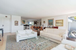 Ein Wohnzimmer mit zwei weißen Sofas, einem Glastisch und einem Teppich mit Muster.