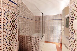 Une salle de bain avec des carreaux décorés, une douche en verre et un plancher en bois.