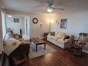 A living room with a sofa, a coffee table, a rocking chair, a clock, and a lamp.