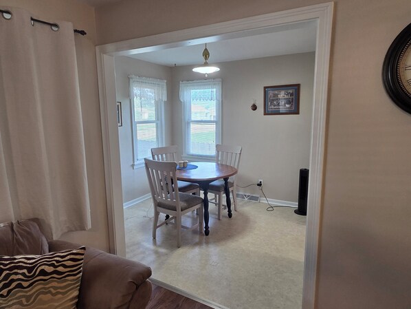 A dining area with a table and chairs, a ceiling fan, and a wall-mounted clock.