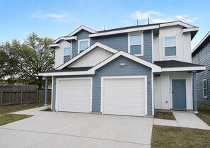 A two-story house with a garage, a front door, and a small porch. - [GS] 6BR + Parking I Two Adjacent Townhomes I Fully Stocked & Family-Friendly (San Antonio)