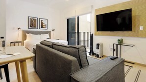 A hotel room with a bed, a sofa, a TV, a small table, and a desk. - w* | Upscale Loft w/ Balcony in Roma Norte (Ciudad de México)