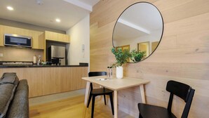 A modern kitchen with wooden cabinetry, a microwave, and a refrigerator. There is a dining area with a table, two chairs, and a potted plant. - w* | Upscale Loft w/ Balcony in Roma Norte (Ciudad de México)