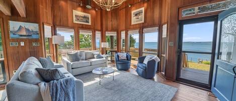 A spacious room with a large window, a chandelier, and a view of the sea.