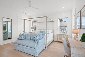Ein Schlafzimmer mit einem Himmelbett, einer Couch, einem Holzschrank und einem großen Spiegel.