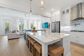 A modern kitchen with white cabinetry, a large island, stainless steel appliances, and a view of the outdoors. - 6BR/6BA w/ Golf cart, Close to Beach and Draper Lake (Santa Rosa Beach)