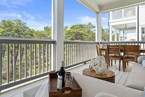 A covered outdoor seating area with a wooden table, chairs, and a bottle of wine. - 6BR/6BA w/ Golf cart, Close to Beach and Draper Lake (Santa Rosa Beach)